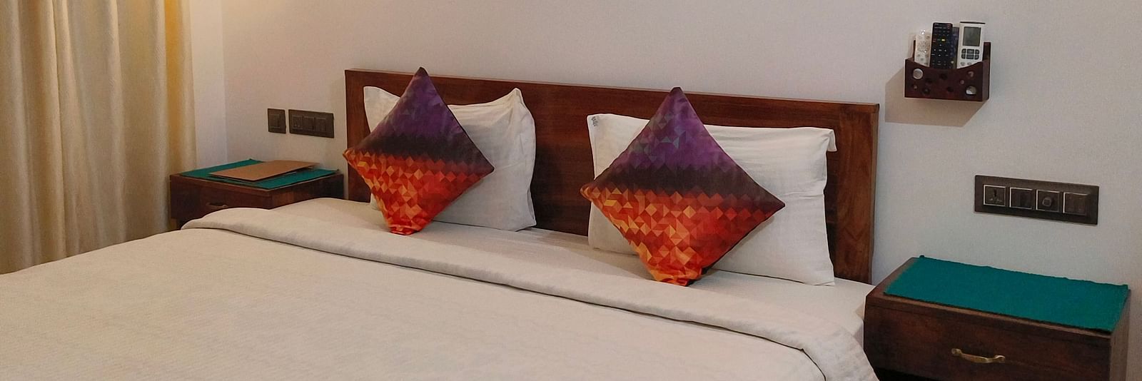 Another view of a double bed with two colourful pillows in 103 room at Ananda Holiday Home, Wayanad 3