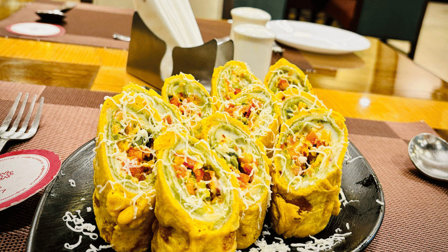 A serving of cheesy bread rolls served at the Navidya Restaurant, placed on a dining table - Amantra Comfort Hotel