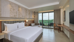 Spacious modern hotel room with king-sized bed, seating area, and balcony view Sarovar Portico Gir