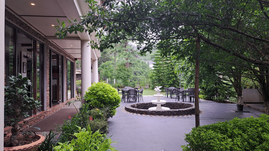 The facade of The Heritage Club featuring a fountain and plants in the surroiunding.