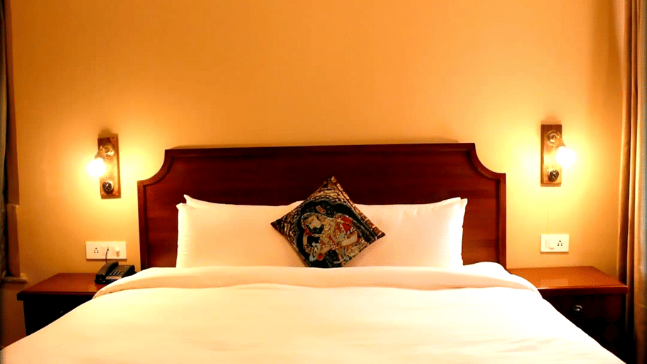 A room with a large bed, spreads, pillows, and lights. | Hotel Devnadi, Haridwar