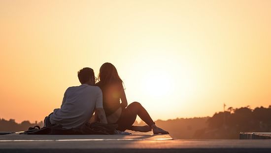 couple sitting on a pavement watching sunset