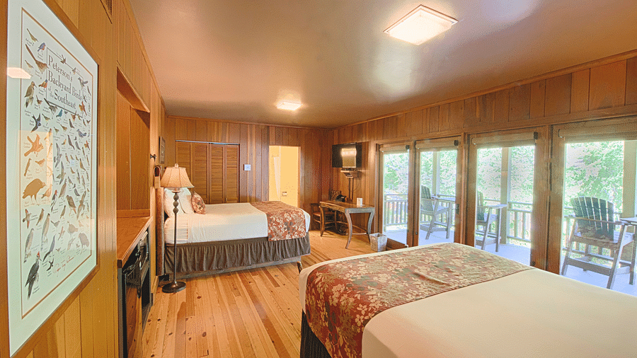 image of a bedroom with wooden flooring featuring huge french windows opening to a private porch - Historic Tapoco Lodge