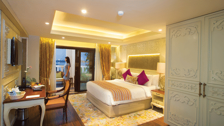  Spacious bed with furniture for seating, a bedside table, and a wall-mounted television at Fragrant Nature Cochin