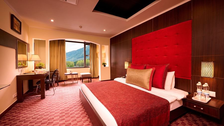 Renest Hotel Manali - Interior view of the canary room with a king size bed in red and brown decor