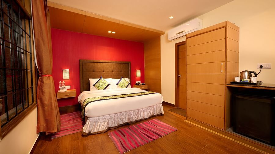 Renest Manali - interior view of a bedroom in Crane cottage featuring a queen size bed in red, brown and white decor