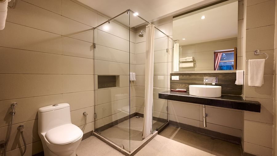 Renest Manali - interior view of the bathroom featuring a commode and  shower area adjacent to a large mirror and sink