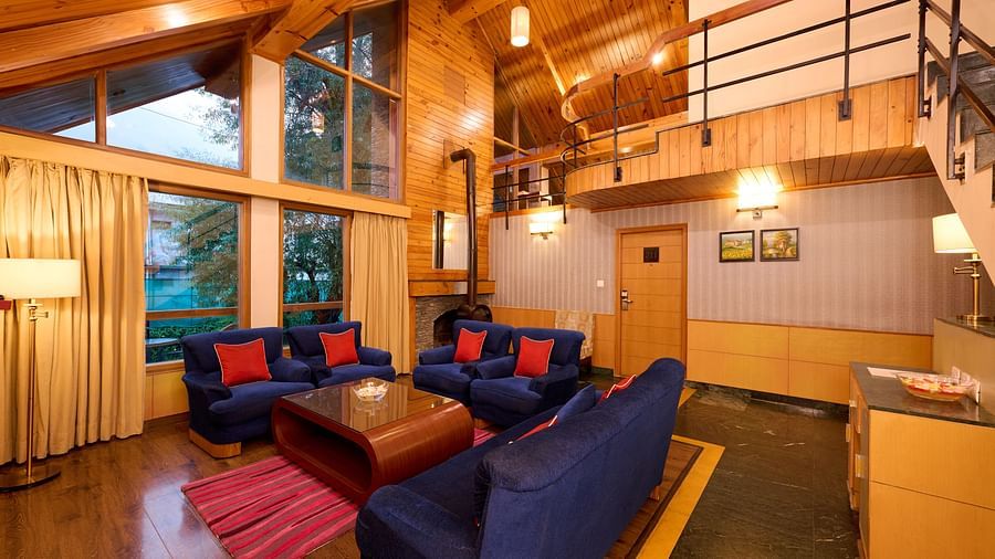 Renest Manali - Interior view of the Hornbill living room featuring a table and blue coloured sofas