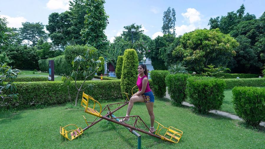 A woman playing on a seesaw in the garden at The Tattwaa Corbett Spa & Resort.