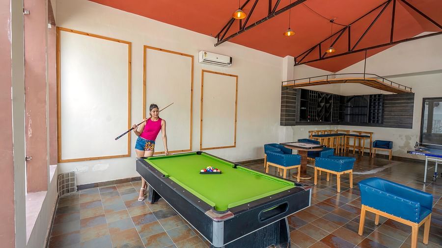 A lady standing beside the pool table, holding a cue stick.