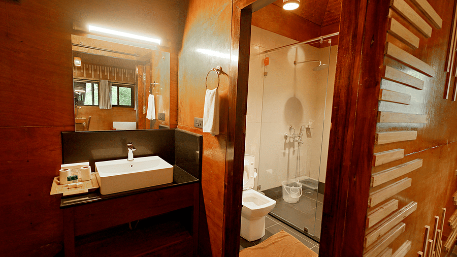 Bathroom with wooden interiors, a large mirror, and modern fixtures at Vythiri Resort, Wayanad