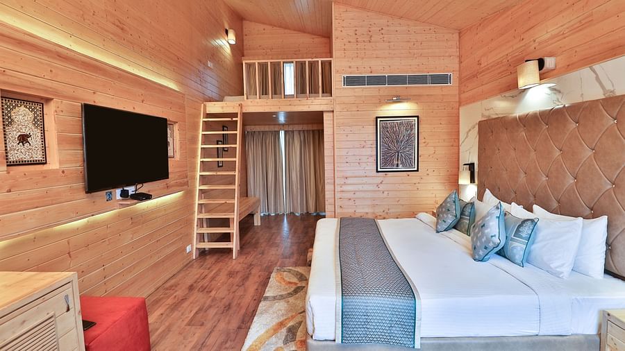 A cosy room with a plush bed, pillows and warm lighting. A ladder leads to a loft area. - Bamboo Saa Resort & Spa, Udaipur