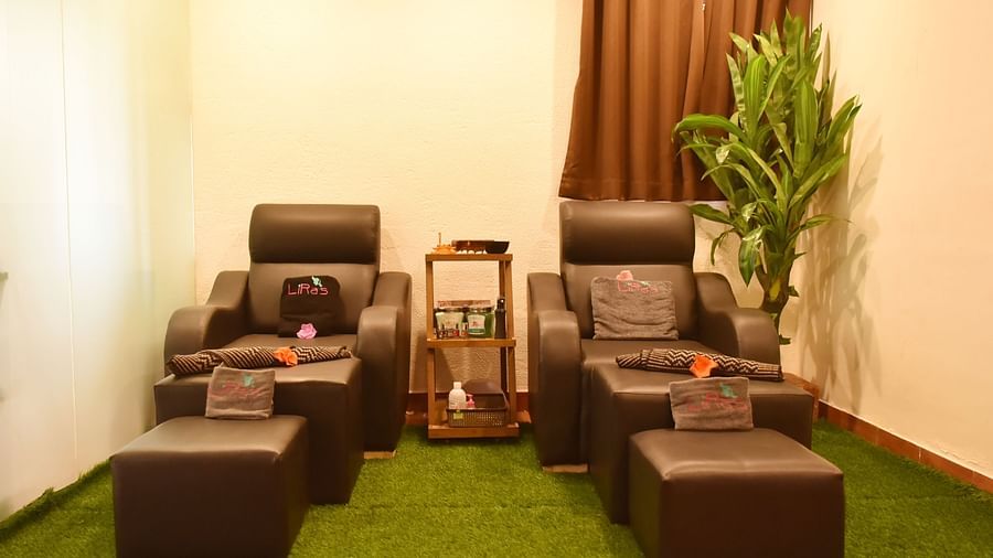 Two comfortable massage chairs with footrests in a relaxing spa setting at Forest Escape, with plants and soft lighting.