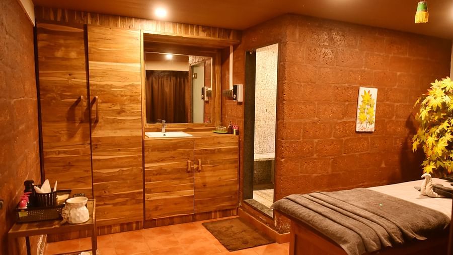 A cozy spa treatment room at Forest Escape, featuring a massage bed, wooden furniture, and warm lighting.