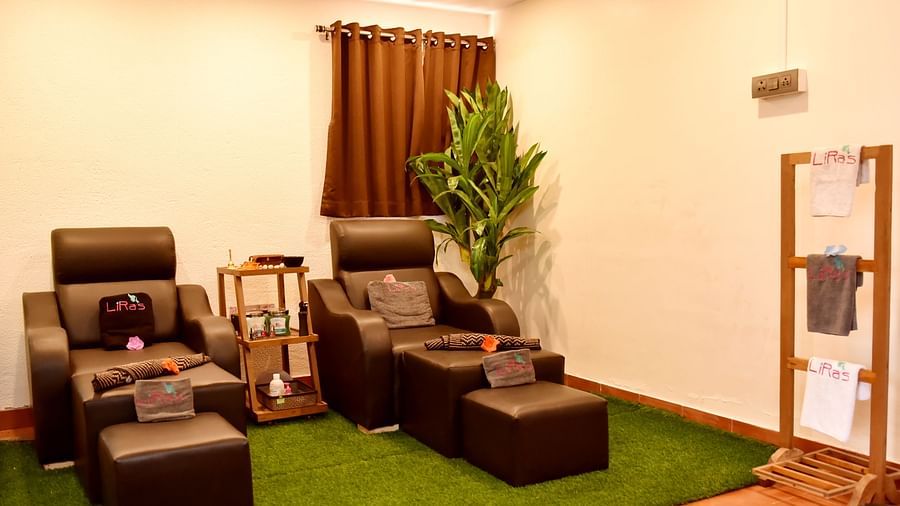 Two plush massage chairs with footrests situated on artificial grass in a tranquil spa environment at Forest Escape.