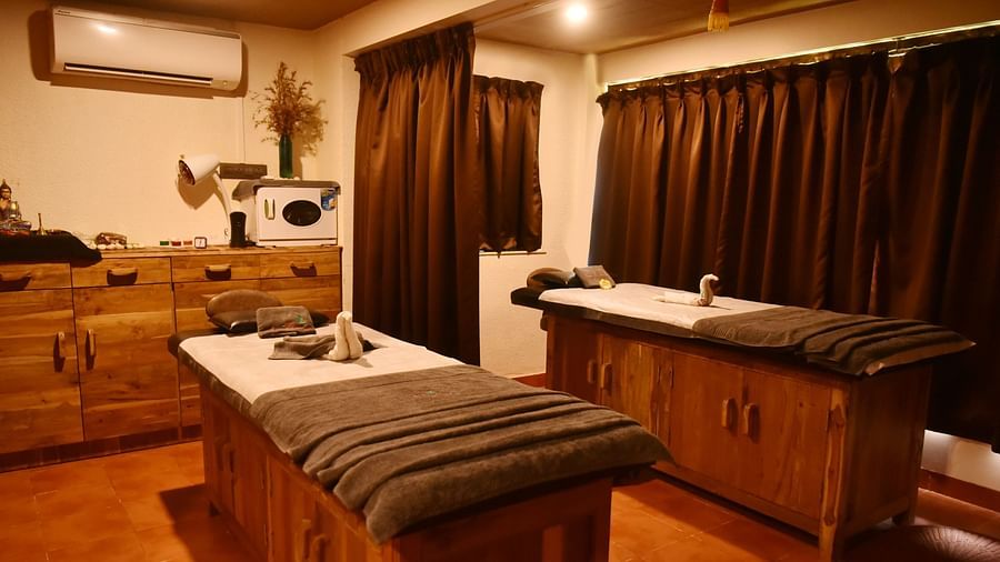 A well-equipped spa treatment room at Forest Escape, with a massage bed, sink, and wooden cabinets.