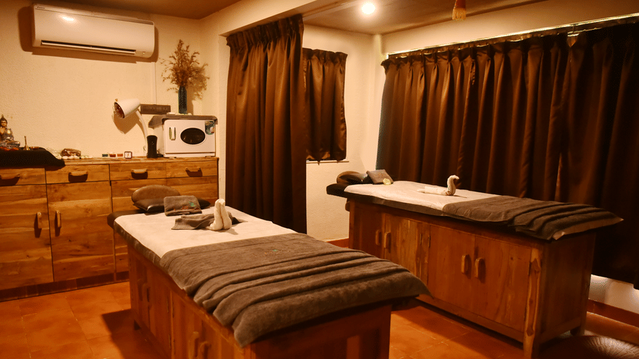 A well-equipped treatment room at the spa in Koyna inside Forest Escapes, with a massage bed, sink, and wooden cabinets.