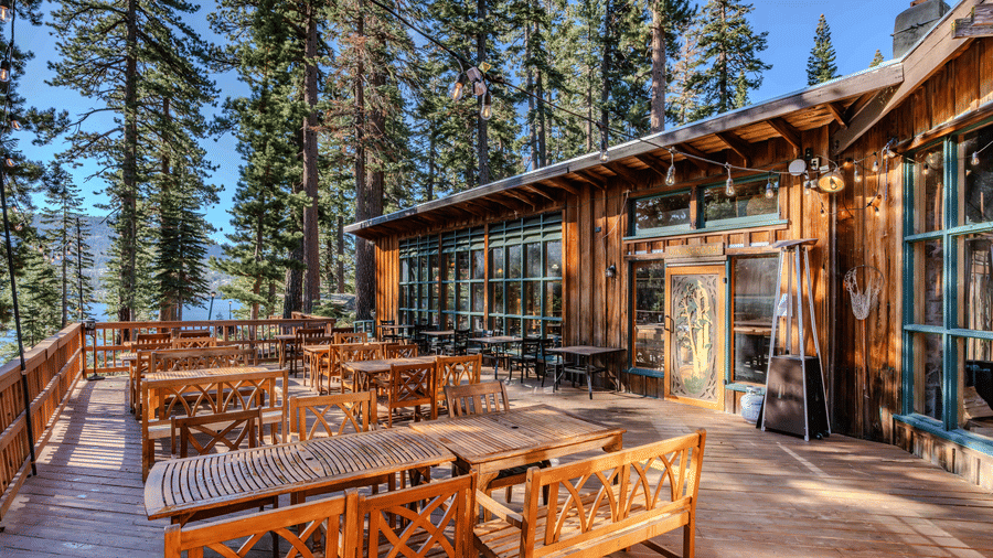 Outdoor dining deck with wooden tables among tall forest trees at our restaurant in Silver Lake | Kit Carson Lodge