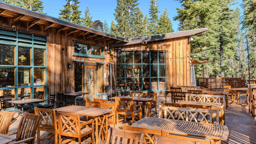 An inviting outdoor seating area at Kit Carson Lodge featuring wooden furniture and scenic forest views