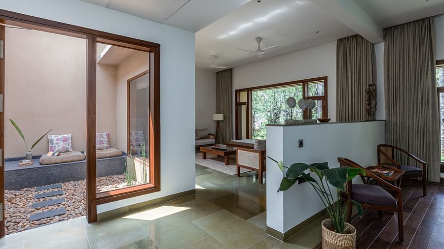 A room with sliding glass doors, a couch, and a view of a garden, bright interior - Shreyas Retreat