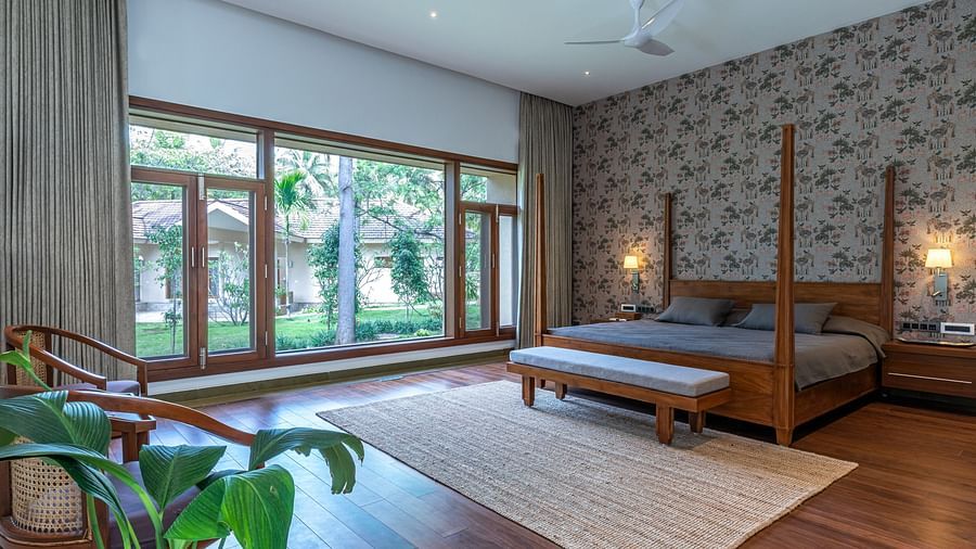 Bedroom with wooden furniture, large windows, rug, indoor plants, natural light - Shreyas Retreat