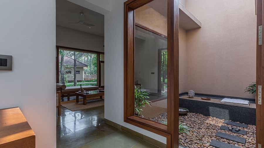 A room with large glass doors leading to a patio with a bathtub, modern interior design - Shreyas Retreat