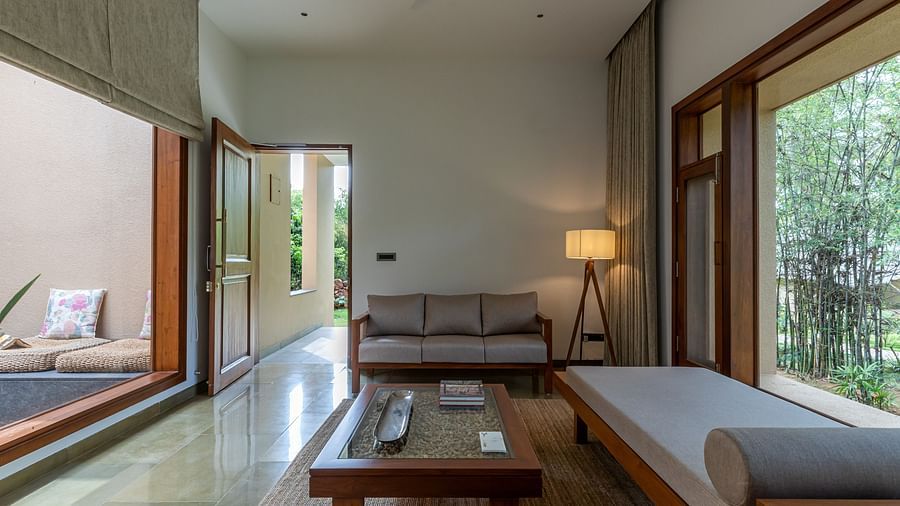Interior room with a bed, couch, and lamp, minimalist design, natural light from windows - Shreyas Retreat