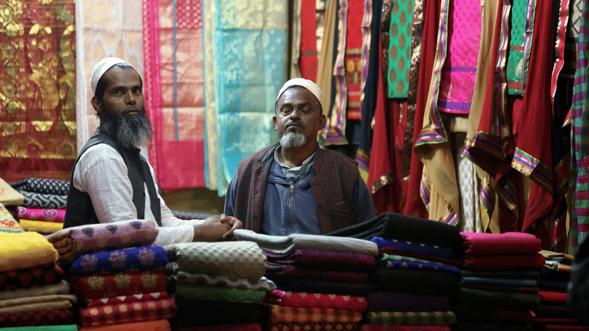 Shopkeepers displaying vibrant handwoven fabrics in a local market.