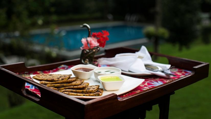 A breakfast tray with pancakes and dips, set up outdoors with a pool in the background.
