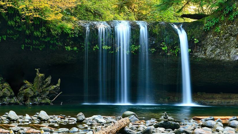 A waterfall cascading down to a waterbody with rock and nature surrounding it