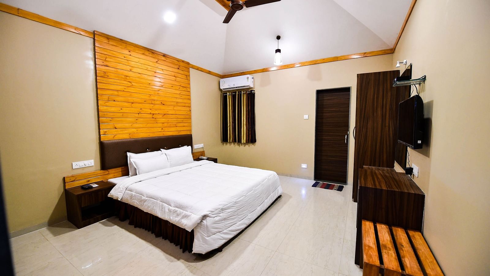 Overview of Deluxe Cottage at the Kanila Resort with a bed, bedside tables, wardrobe and a  ceiling fan.