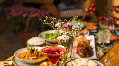 Table at Karma Chalets with a variety of plated dishes including salad, grilled meats, and desserts in a low-lit dining setup.
