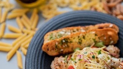 Pasta dish with grilled bread and cheese on a grey plate placed on a wooden surface at Karma Chalets.