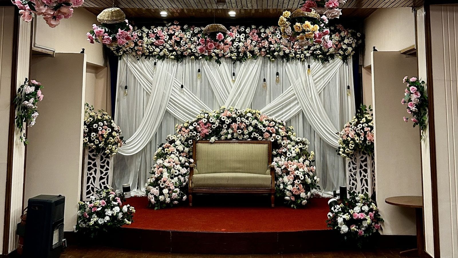 Floral ceiling decor with backdrop setup for wedding ceremony at Cedar Inn, Darjeeling, in an indoor event space.