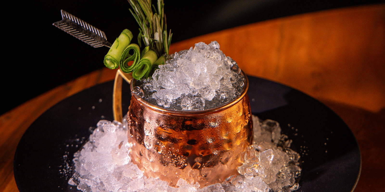 A copper mug cocktail served on a bed of crushed ice, garnished with fresh herbs and a cinnamon stick at Papaya Tree Hotels.