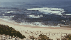 A beach with pristine waters, clean sands, and a cloudy sky where waves meet the shore, available through hotel packages in Mumbai