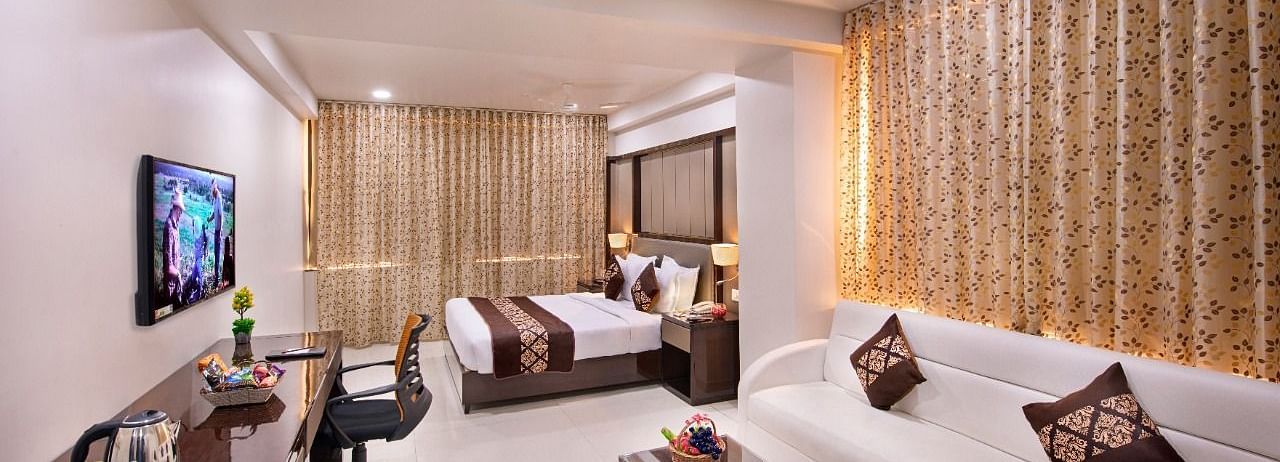 A room at Lords Inn Porbandar, combines a sleeping area with a bed, a seating area with a sofa, and a work desk.