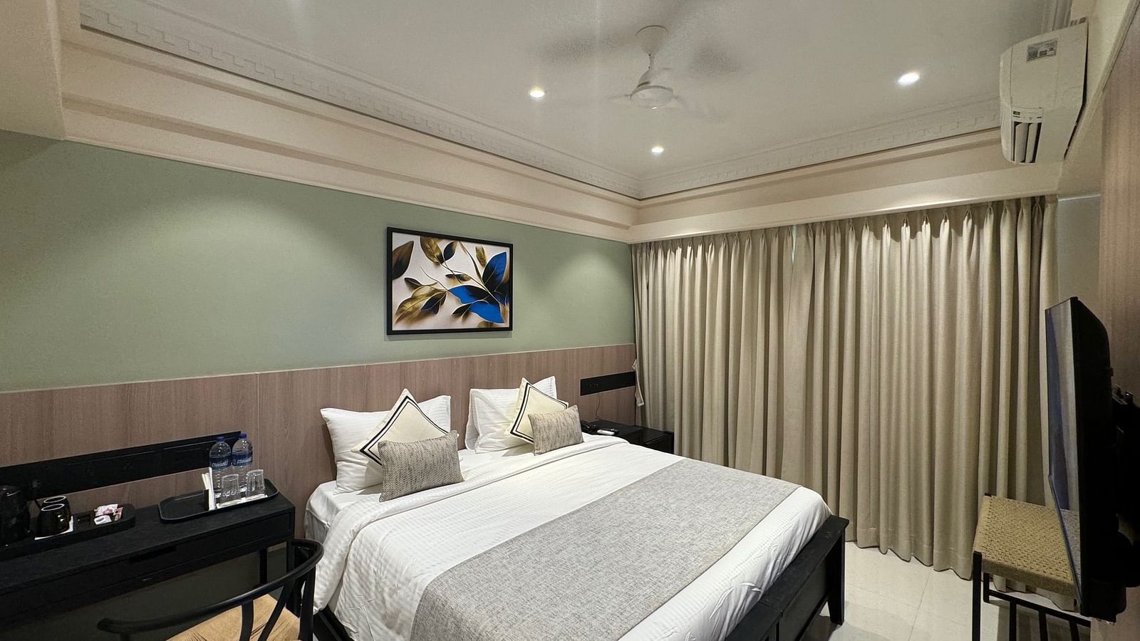 Overview of the superior room with a king bed, side table and a paiting hung above it - Hotel Mumbai House, Valnai, Malad