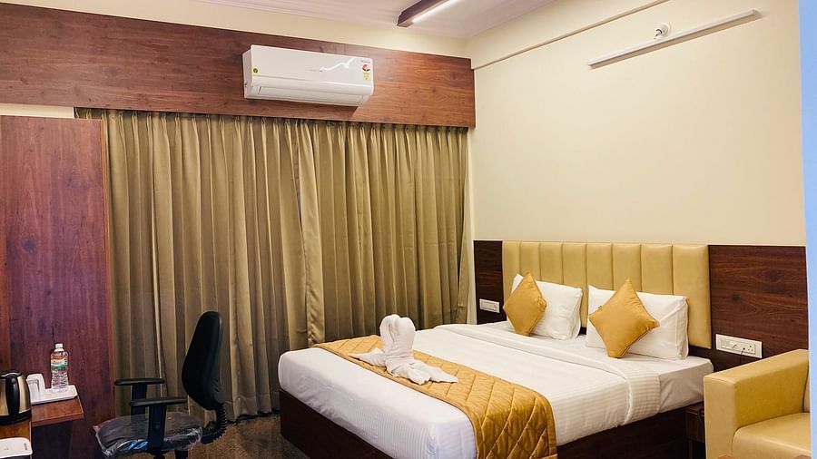Warm, inviting bedroom with elegant curtain backdrop and work desk at Hotel Sahara Tree.