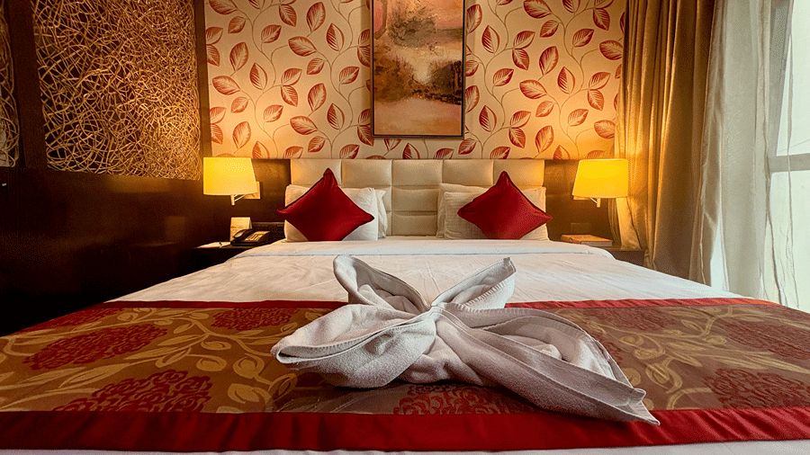 Front close-up view of King-size bed with, a folded towel placed on top, and bedside tables at the Executive Suite at Senses Hotel.