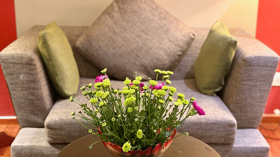 A well-cushioned sofa with a centre table on which a flower vase is placed in the separate sitting area in the Executive Suite at Senses Hotel.