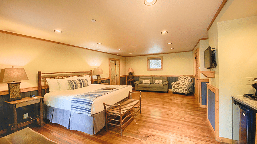 a room featuring a flat screen television wall mounted in front of a double bed along with a plush couch in the corner - Historic Tapoco Lodge