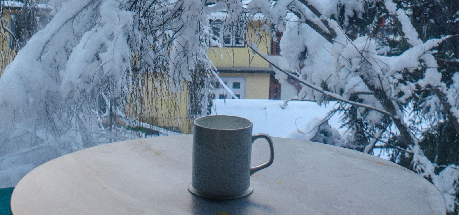 a mug on a table with snowy trees in the background