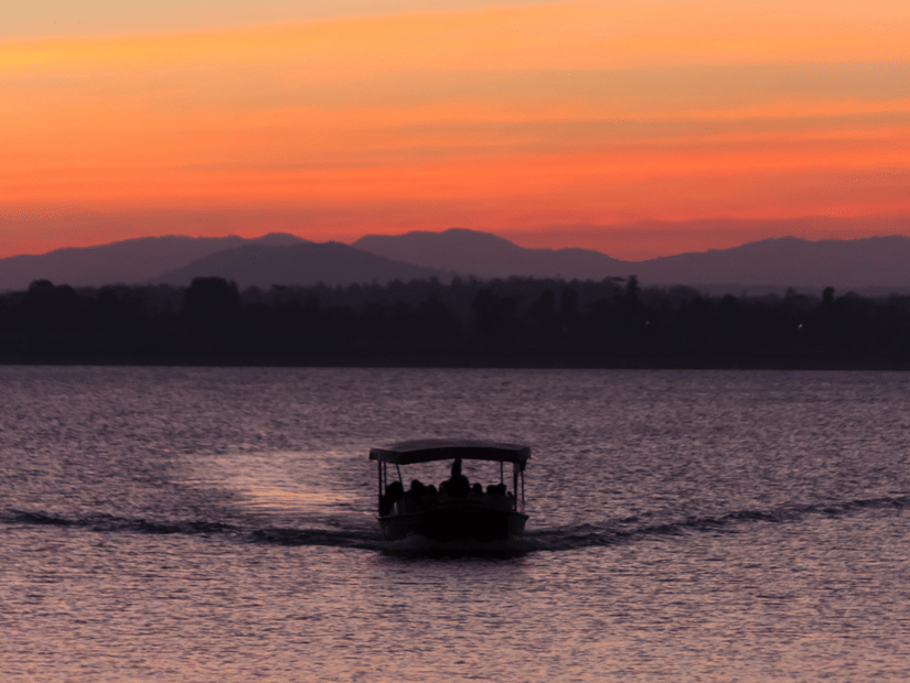 A twilight view of a boat travelling towards the camera with different hues in the sky after the sunset.