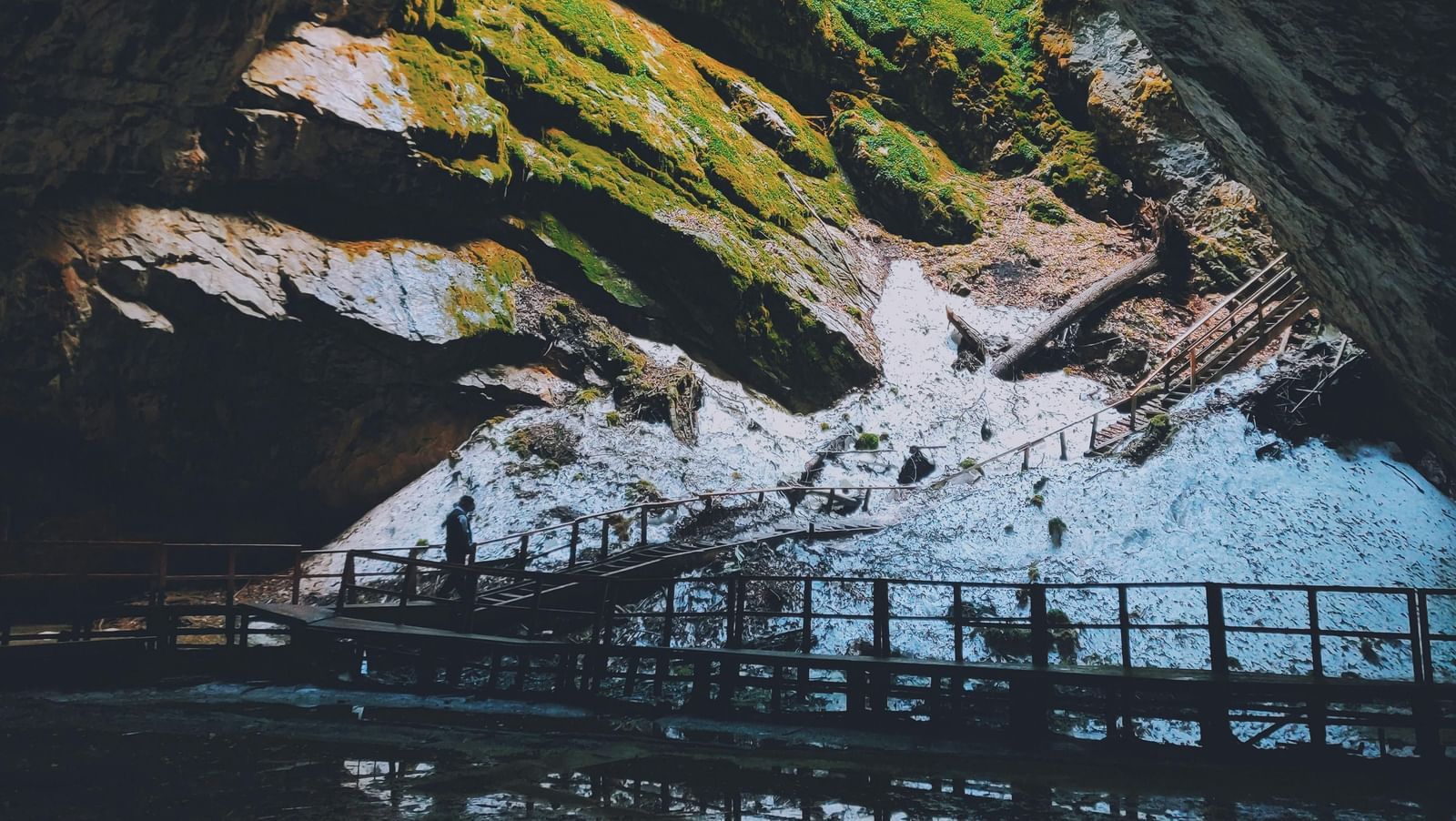Inside of a cave with a pathway gaurded with hand rails surrounded by a shallow water body.