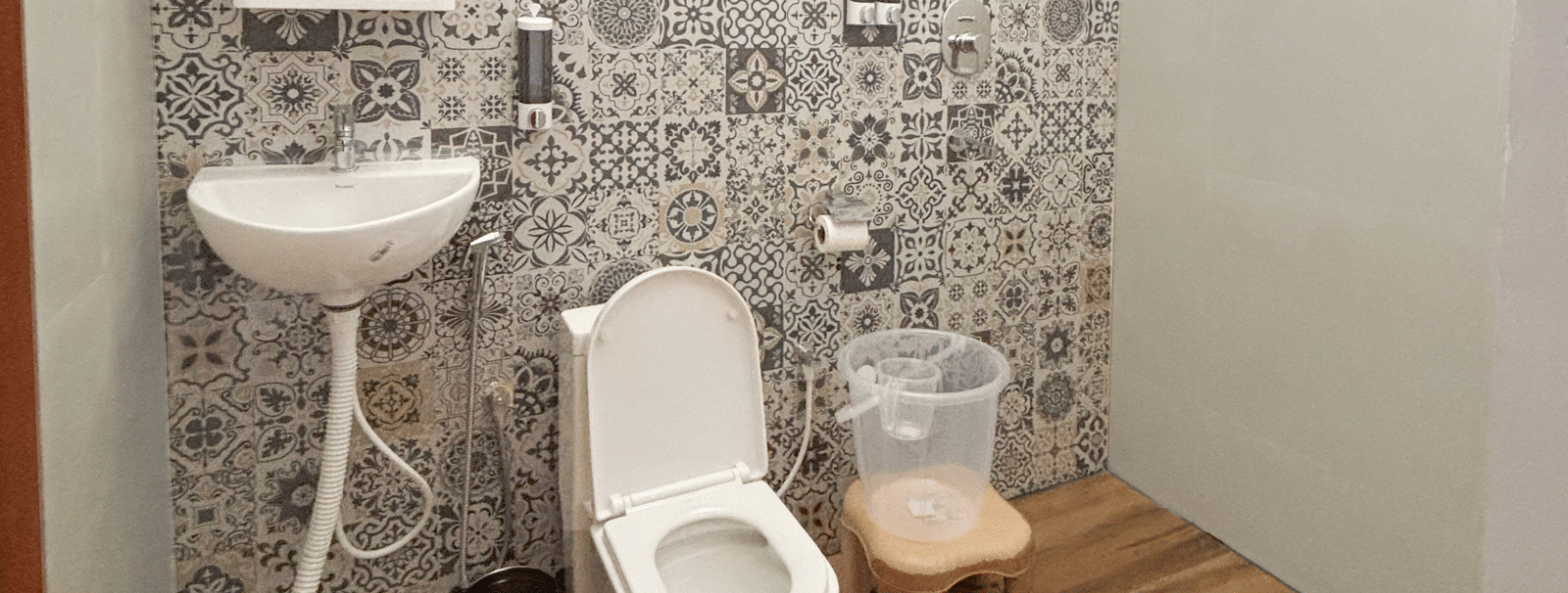 A compact bathroom featuring a ventilation window near the ceiling along with a commode and a wash basin at WOW Naturefull Resorts, Yercaud.