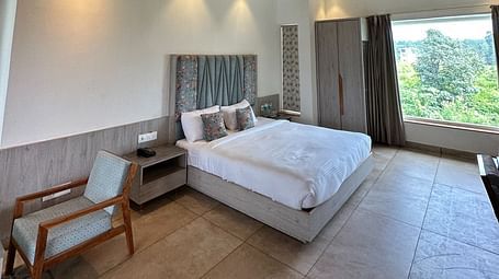 A modern hotel room with a king size bed, a wooden ceiling, and a staircase leading to an upper level.