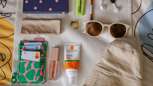 A tote bag with various travel essentials placed on it.