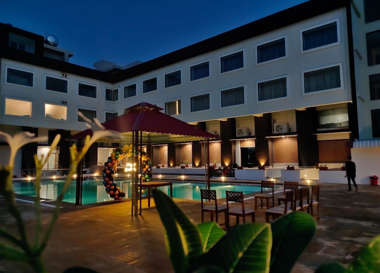 An evening view of a resort building with illuminated windows surrounding a swimming pool - Bamboo Saa Mulberry Resort, Pushkar