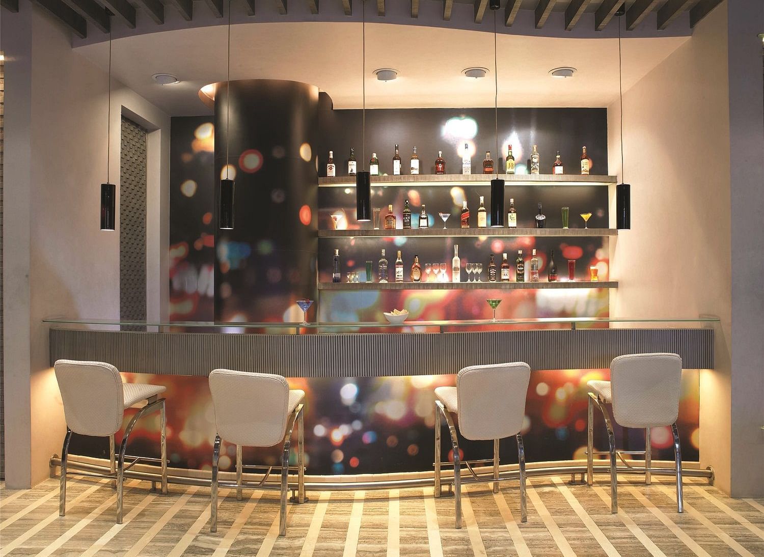 Image of zebra lounge at our hotel featuring a bar stand with chairs and bottles of alcohol | Mirage Hotel